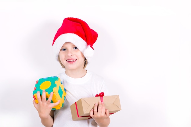 Garçon heureux au chapeau rouge de Santa tenant le cadeau de Noël à la main. Notion de Noël.