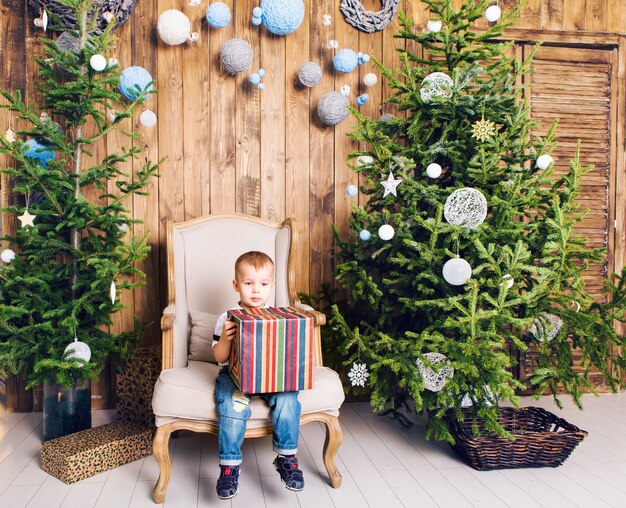 Garçon heureux avec le cadeau de Noël près de l'arbre de Noël