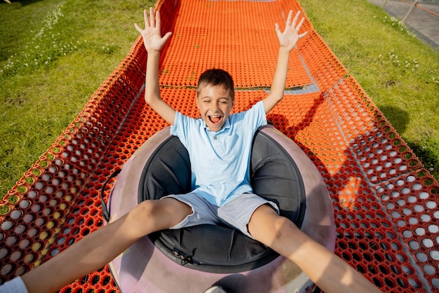 Un garçon heureux descend dans un tube de luge gonflable au parc d'attractions