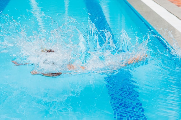 Garçon heureux enfant sautant dans la piscine