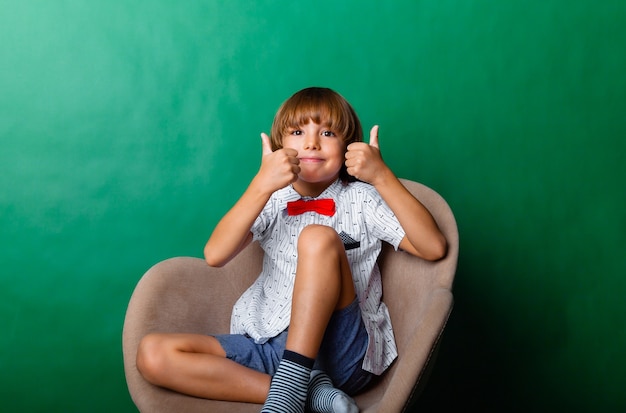 Un garçon heureux est assis sur une chaise et montre la classe. Concept éducatif et scolaire