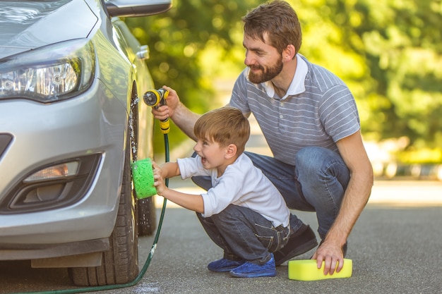 Le garçon heureux et un père lavent une voiture