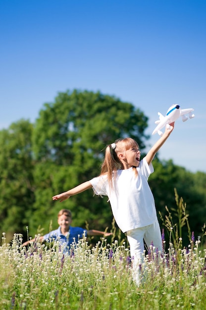 Photo un garçon heureux et une petite fille avec un avion sur un pré par une journée ensoleillée.