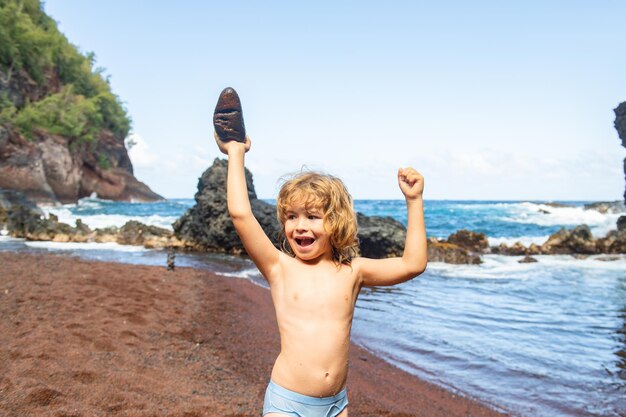 Un garçon heureux tient des pierres sur la côte de la mer. Jeux de plage avec enfants. Loisirs le soir en vacances avec les enfants. Enfance. Concept de vacances et de voyage pour enfants.
