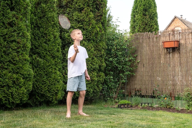 Un garçon heureux tient une raquette de badminton dans ses mains activités de plein air