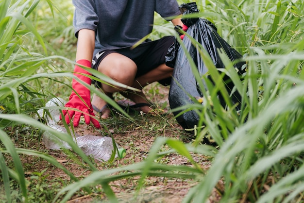 Garçon homme main ramasser une bouteille en plastique dans la forêt. concept de conservation de la nature et de l'environnement.