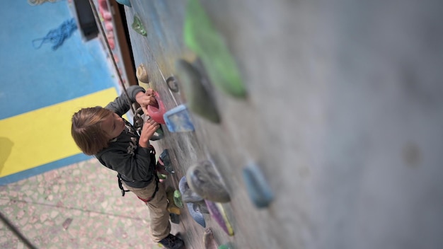 Un garçon de huit ans grimpe le mur d'escalade dans le hall