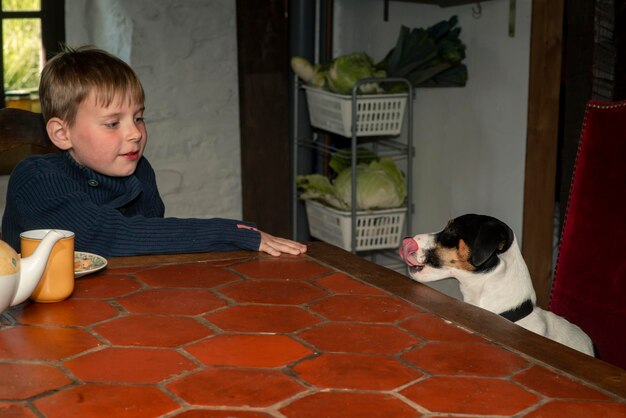 Un garçon de huit ans mange à une table avec un chien