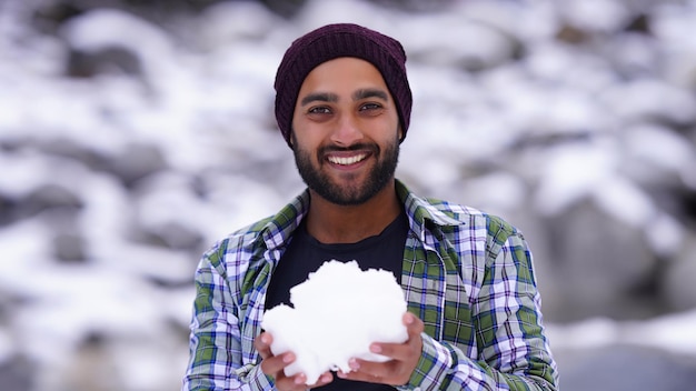 Garçon indien appréciant et jouant avec la neige pendant les chutes de neige d'hiver