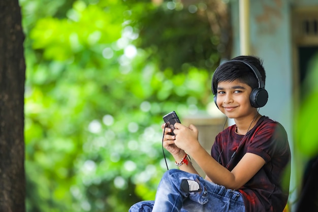 Garçon indien écoutant de la musique ou apprenant sur téléphone mobile