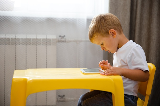 Garçon jeune enfant jouant ou regarder le dessin animé sur la tablette à l'intérieur.