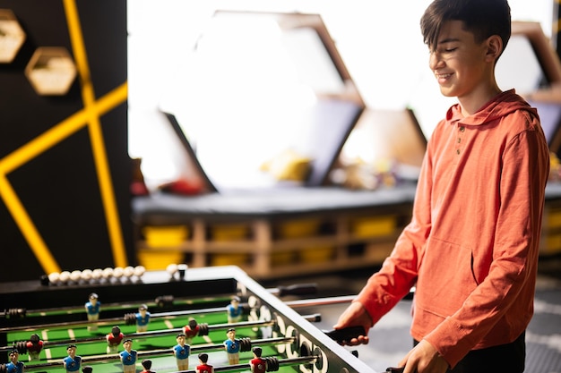 Garçon jouant au baby-foot dans le centre de jeux pour enfants