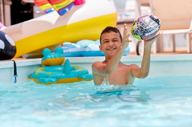 Garçon jouant avec des balles à la piscine. Photo de haute qualité