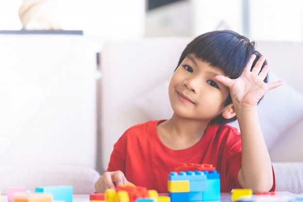 Garçon jouant des blocs de jouets dans le salon avec la main dire bonjour