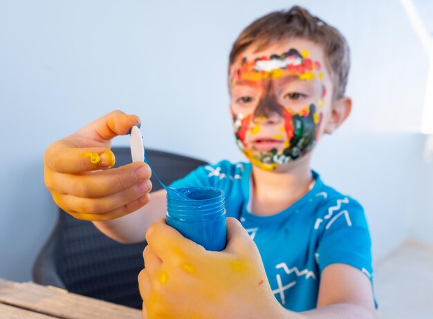 Garçon jouant avec les couleurs en utilisant ses mains et son visage