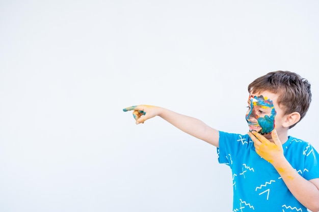 Garçon jouant avec les couleurs en utilisant ses mains et son visage