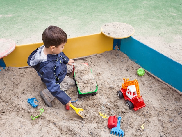 Garçon jouant dans un bac à sable