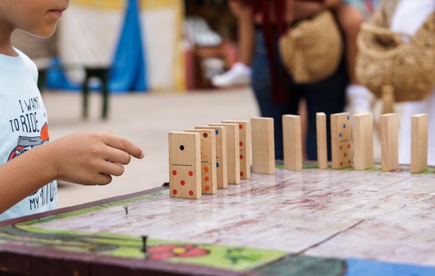 Garçon jouant avec des dominos en bois à l'extérieur