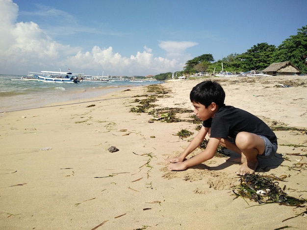 Un garçon jouant avec du sable sur la plage.