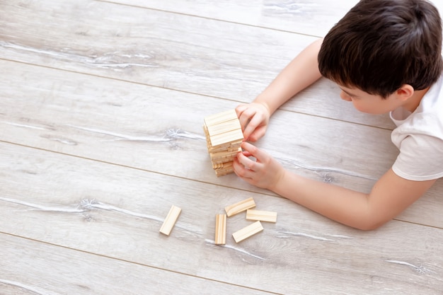 Garçon jouant un jeu de Jenga sur le sol