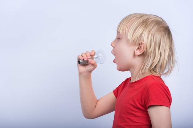 Garçon Jouant Avec Une Lampe à Incandescence. L'enfant Chante Dans Une Ampoule Comme Dans Un Microphone