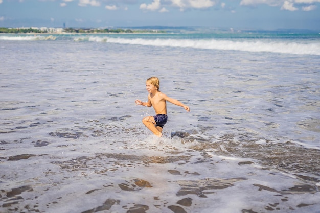 Garçon jouant sur la plage dans l'eau