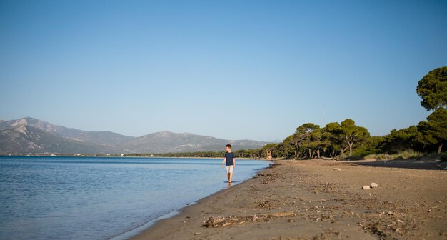 Garçon jouant sur la plage pendant les vacances d'été Enfants dans la nature avec du beau sable de mer et bleu courant dans l'eau de mer