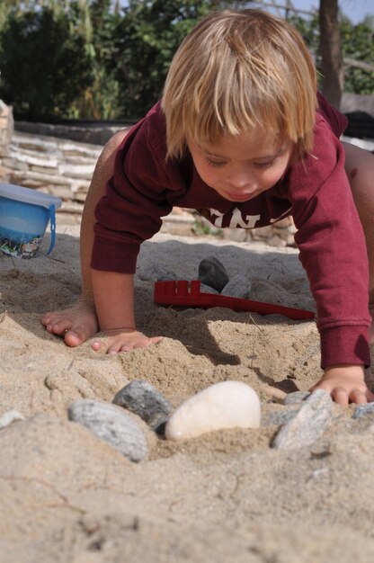 Photo un garçon jouant sur le sable.