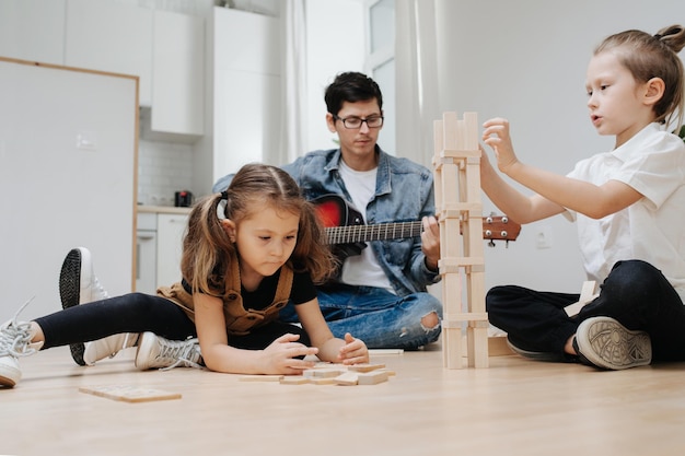 Garçon jouant sur le sol avec des blocs Papa jouant de la guitare en arrière-plan