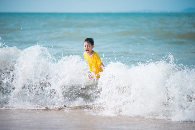 Garçon jouant des vagues et du sable sur la plage