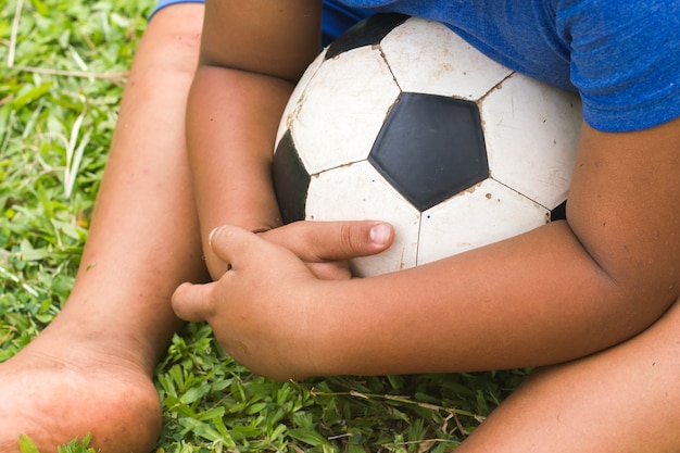 Photo garçon joue au football dans le champ d'herbe.