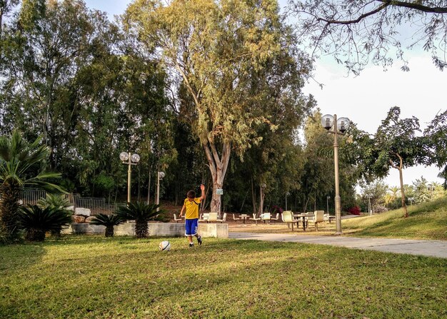 Photo un garçon joue au football dans le parc.