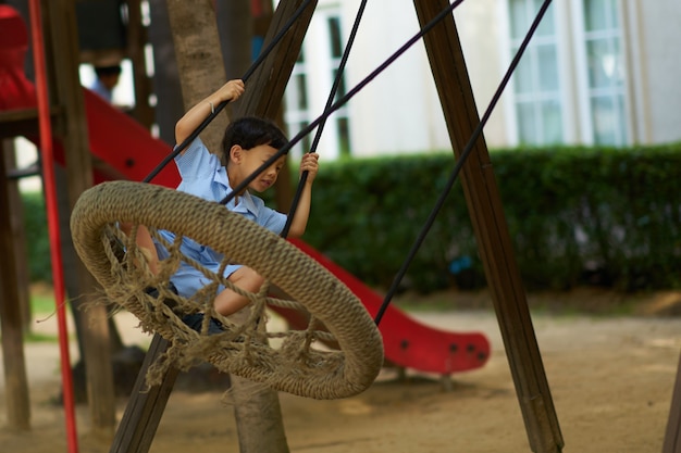 Un garçon joue au swing dans la cour d&#39;école