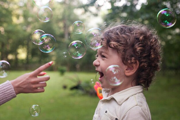 Photo un garçon joue avec des bulles dans le parc.