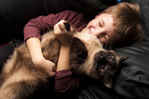 Un garçon joue avec un chat.