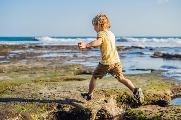 Le garçon joue sur la plage cosmique de Bali.. Touriste de voyage de portrait. Émotions humaines positives, modes de vie actifs. Heureux jeune garçon sur la plage de la mer