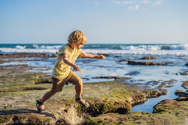 Le garçon joue sur la plage cosmique de Bali.. Touriste de voyage de portrait. Émotions humaines positives, modes de vie actifs. Heureux jeune garçon sur la plage de la mer