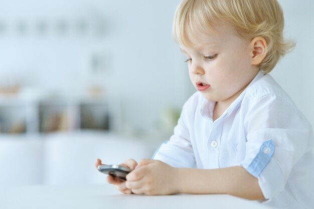 Le garçon joue avec un téléphone portable