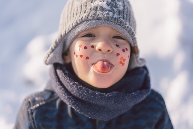 Garçon joyeux avec des coeurs rouges sur son visage