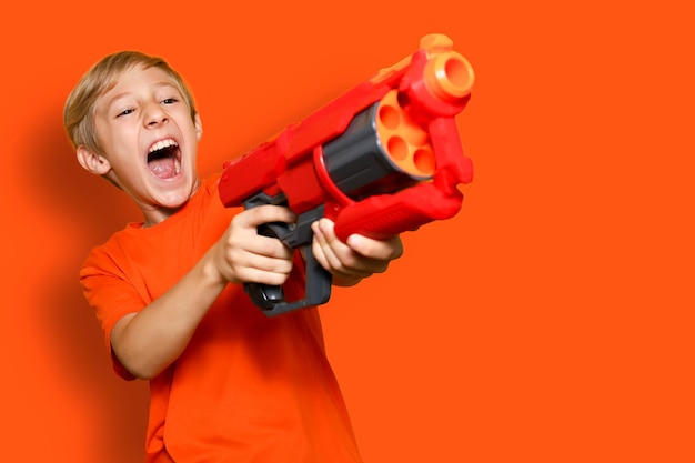 Un garçon joyeux avec un pistolet jouet crie