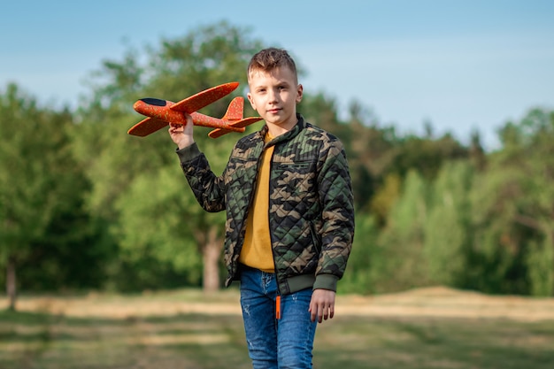 Le garçon lance un avion jouet.