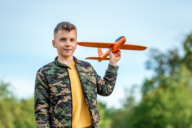 Le garçon lance un avion jouet.