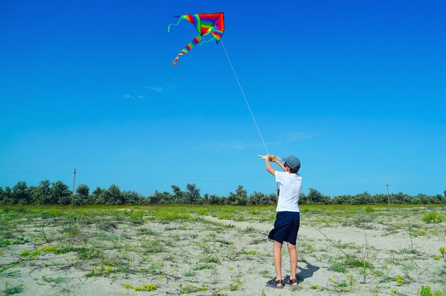 Un garçon lance un cerf-volant sur la côte de la mer.