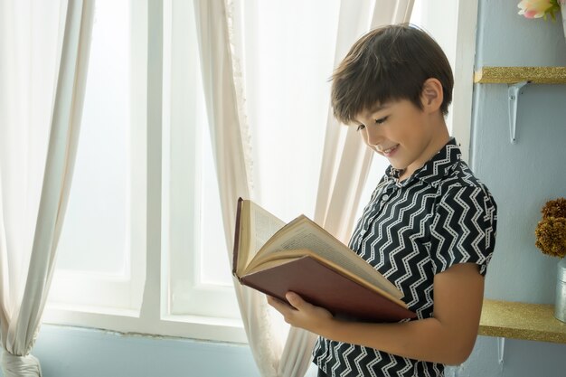 Garçon, lecture d&#39;un livre dans la chambre