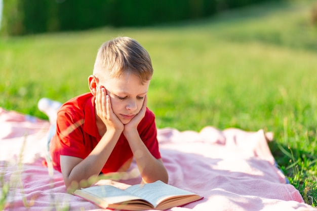 Garçon lisant un livre dans le parc sur fond de verdure