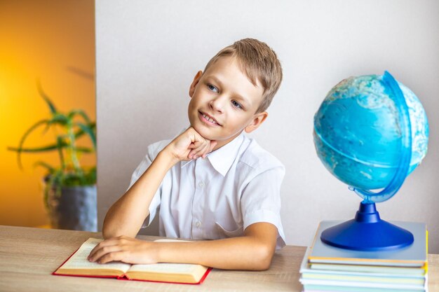 garçon lisant un livre sur le fond du globe assis à la table