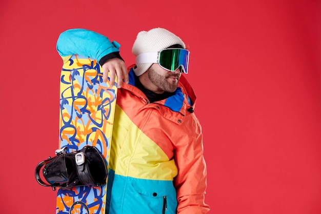 Garçon avec des lunettes de neige s'appuyant sur un snowboard