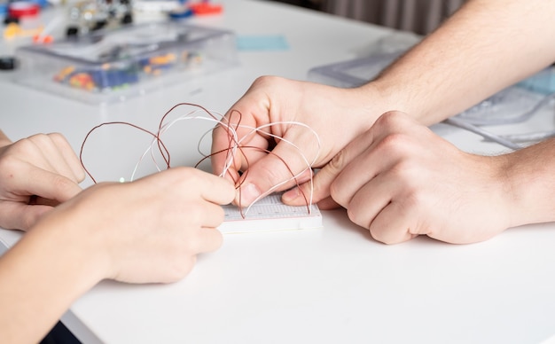 Garçon mains travaillant avec des lumières LED sur un tableau expérimental pour un projet scientifique