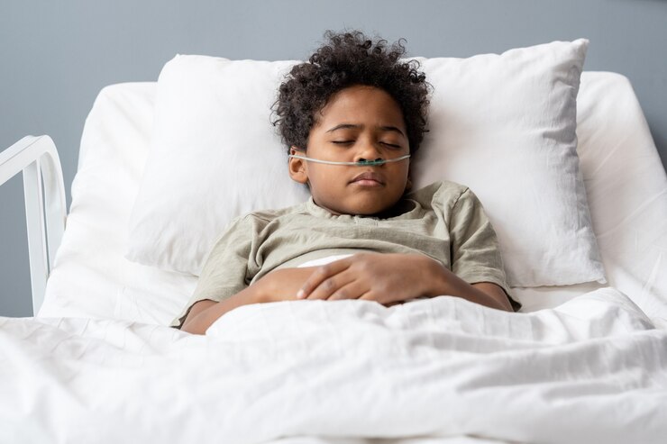 Garçon malade dur avec des tubes dans son nez dormant dans son lit à l'hôpital