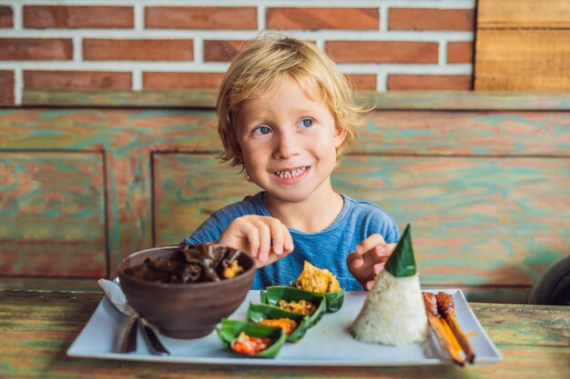 Garçon mange dans un café. Mode de vie. Un plat composé de riz, de poisson frit aux champignons des bois et de différentes sortes de sauces.